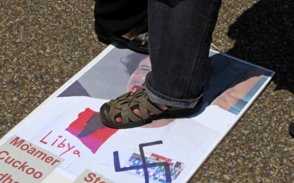 People step on a poster with an image of Muammar Gaddafi during an anti-Gaddafi demonstration in front of the White House, July 9, 2011. Photo: Wikimedia Commons/Ben Schumin